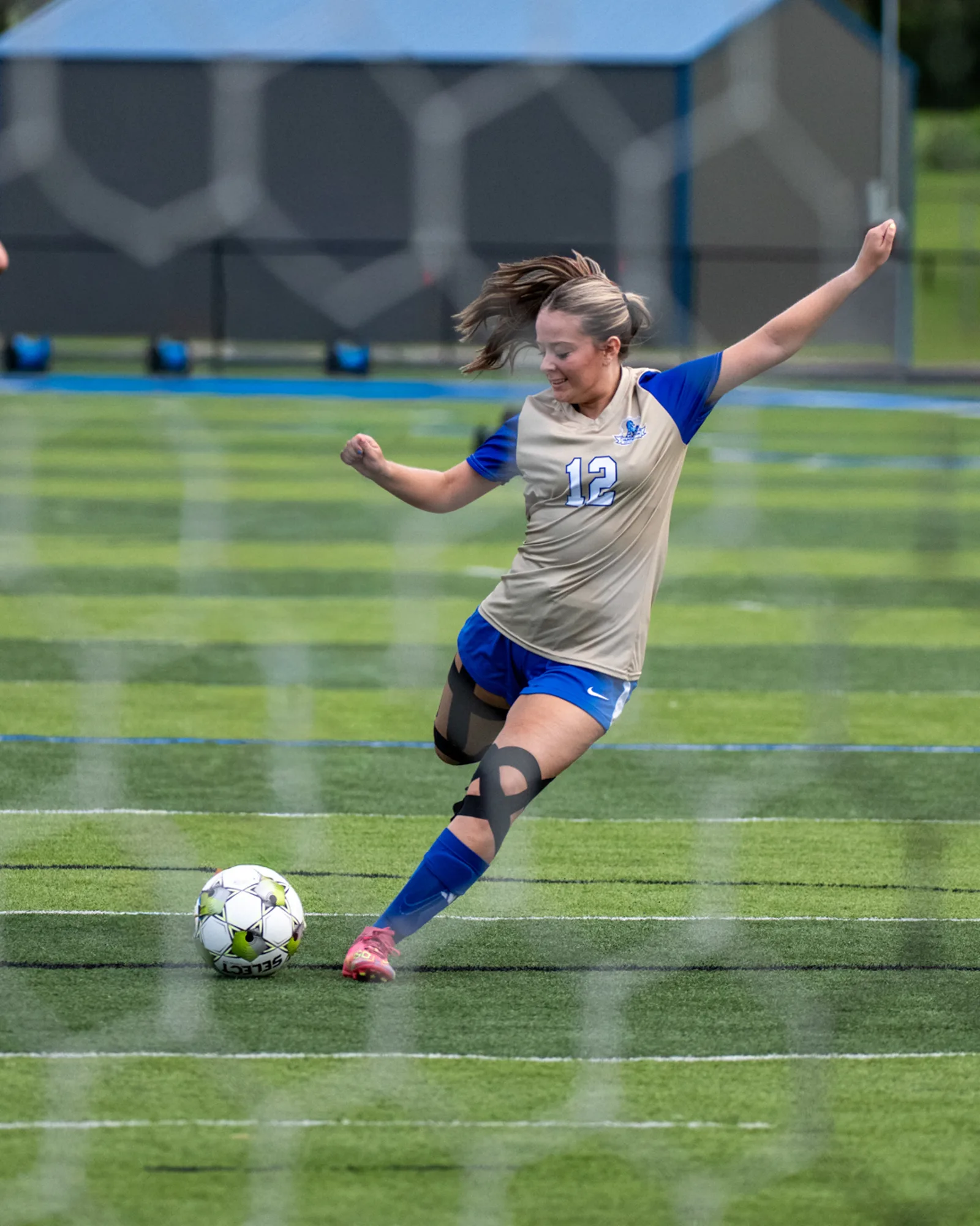 Girls soccer player winding up to strike the ball on a turf field