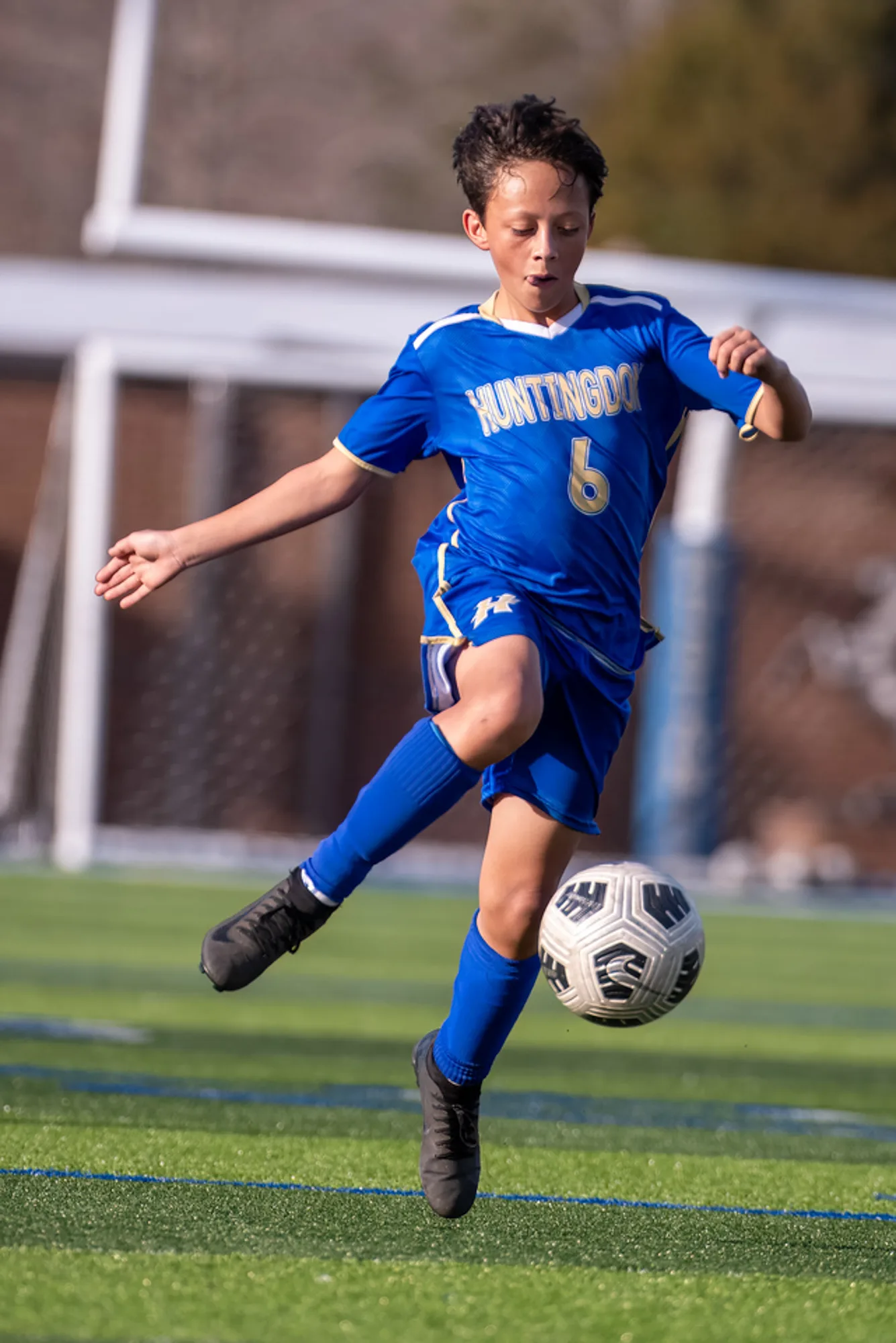 Boys soccer player in a blue Huntingdon kit controlling the ball in mid-air