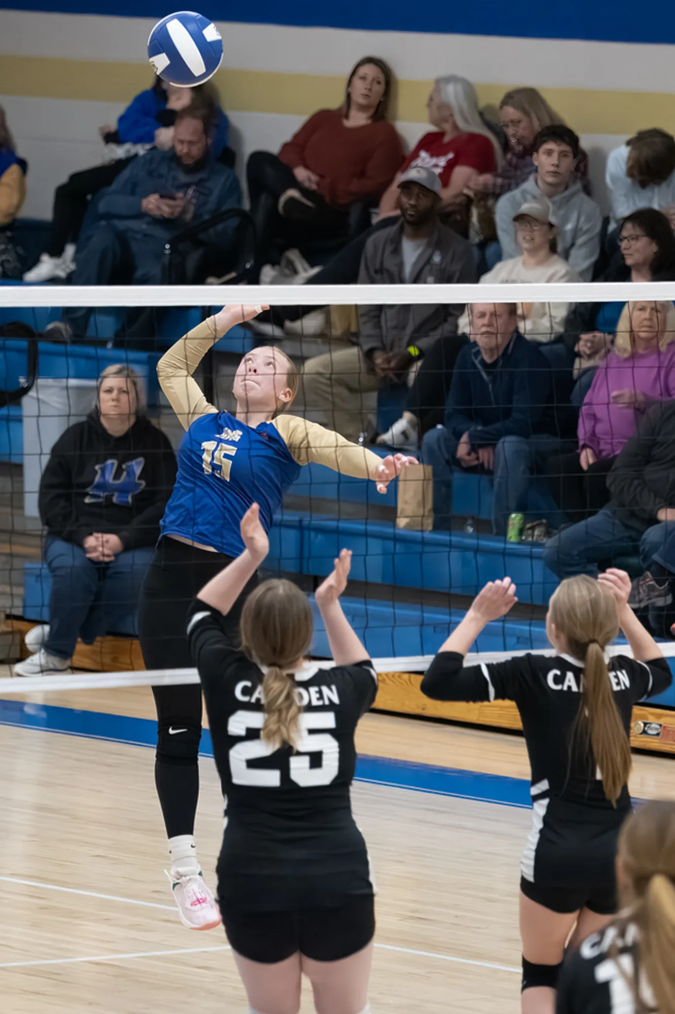 Volleyball player rising to spike the ball over the net past two blockers